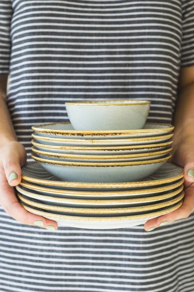 A pile of blue worn dishes in female hands. Tableware concept