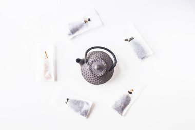 Farklı çaylar bir pik döküm su ısıtıcısı beyaz zemin üzerine yanında bira için bir tek kullanımlık filtre torbaları. Üstten görünüm, düz yatıyordu