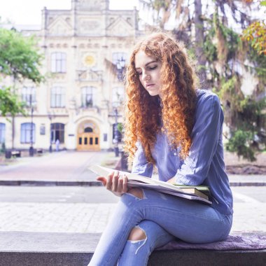 Bir defter ile eğitim notları bakarak onun university yakınındaki oturan beyaz Kızıl saçlı kıvırcık saçlı kız. Çalışma kavramı