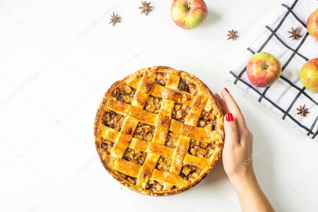 Traditional American apple pie with dough decoration in a grid in female hands on a white table. Autumn baking concept. Minimalism. Top view, flat lay