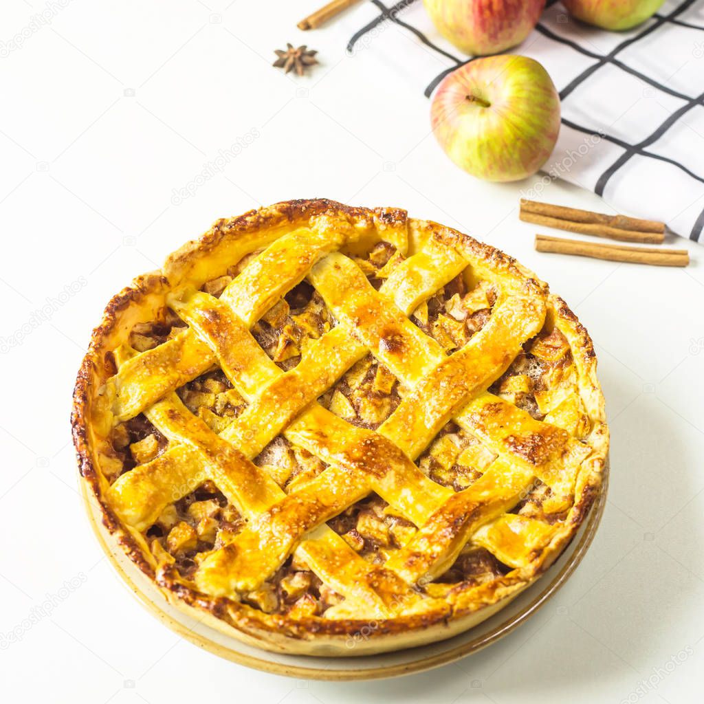 Traditional American apple pie with dough decoration in a grid on a white table. Autumn baking concept. Minimalism. Top view, flat lay