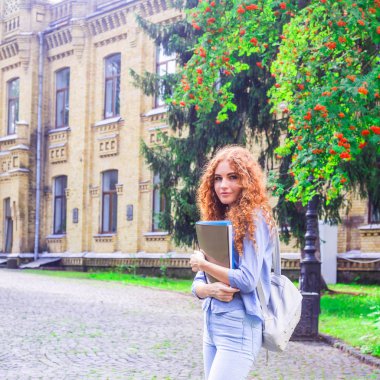 Kızıl saçlı kız öğrenci klasörleri ve öğretim materyalleri üniversitenin yanında elinde. Geri okul kavramı. öğrenci yaşamı