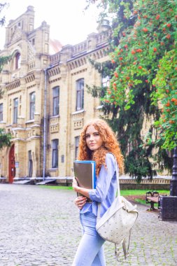 Kızıl saçlı kız öğrenci klasörleri ve öğretim materyalleri üniversitenin yanında elinde. Geri okul kavramı. öğrenci yaşamı