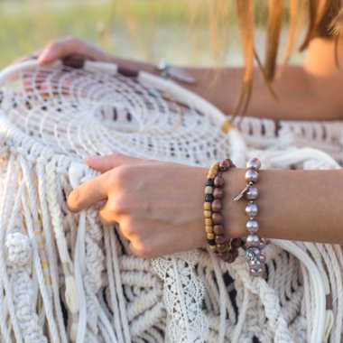 Bir kız çimenlerin üzerinde oturur ve bir rüya avcısı - makrome beyaz konuları yapılmış bir aksesuar tutar. Yavaş hayat ve bir güzel dekor kavram oluşturma