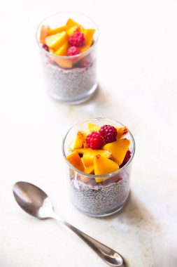 Hindistan cevizi sütü ile ahududu ve şeftali cam kavanoz beyaz bir tablo üzerinde Chia puding. Sağlıklı çiğ vegan gıda