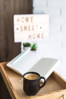 Bir fincan kahve ve bir ahşap tepsi daire parlak iç açık bir defter. Dekoratif çerçeve üzerinde yazılı evim güzel evim