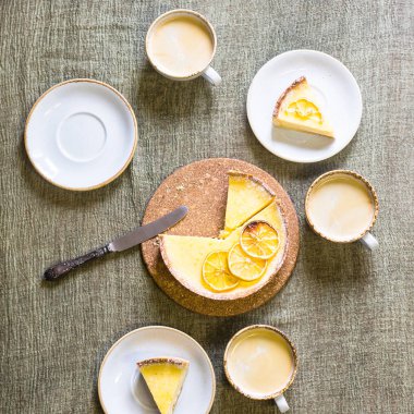 Daireler ve bardak kahve arasında masadaki limon tart. Ev yapımı hamur işleri ve ev yapımı zevkli. Üstten görünüm, düz yatıyordu