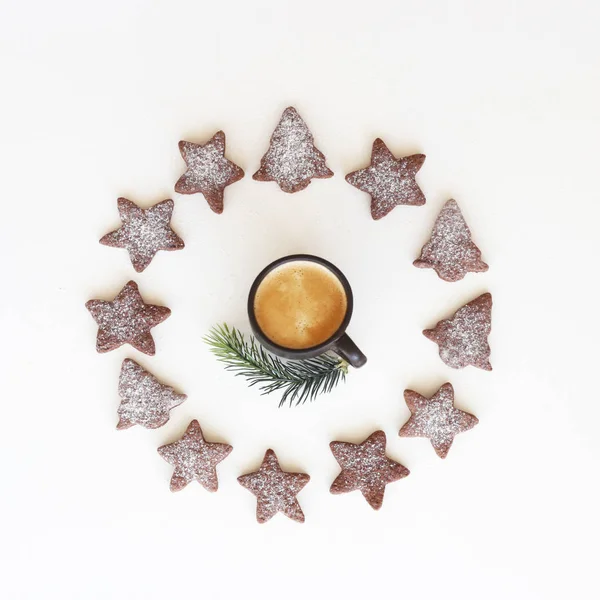 在一棵圣诞树的形状上的姜饼饼干和有糖衣的星星在一杯咖啡周围围着一圈 上面有一个白色背景的冷杉树枝 圣诞节和新年在简约风格的顶部视图 — 图库照片