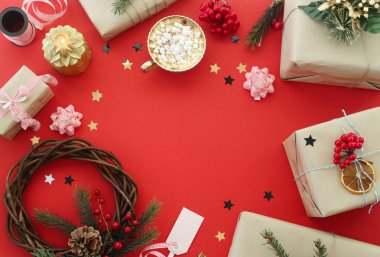 Noel çelenk ve hediyeler arasında süslemeleri yanında bir fincan kakao marshmallows kırmızı bir arka plan ile. Kopya alanı