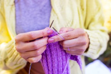 Örgü iğneleri örme kadın elinde için lila rengi öğeleri ördü. İğne işi hobi kavramı. Sonbahar sıcak el yapımı giyim. Yakın çekim