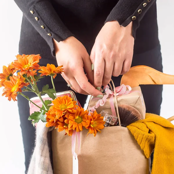 Crafts package with women's shopping on black Friday, filled with clothes, cosmetics, flowers in the hands of a girl in black clothes