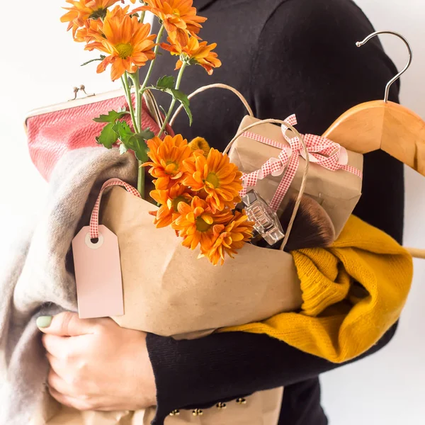 Crafts package with women's shopping on black Friday, filled with clothes, cosmetics, flowers in the hands of a girl in black clothes