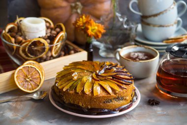 Kuru üzümlü kek Sonbahar dekorasyonu - kabak, mum, portakal ve sarı kasımpatı arasında dilimlenmiş erik ile dekore edilmiştir. Rustik tarzı. Kendinizi evinizde gibi hissedeceğiniz rahat natürmort