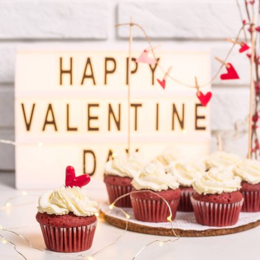 Sevgililer günün kutlu olsun yanında kırmızı top kek dekoratif lamba üzerinde bulunmakta. Kırmızı kadife mascarpone krema ile. Sevgililer günü kavramı