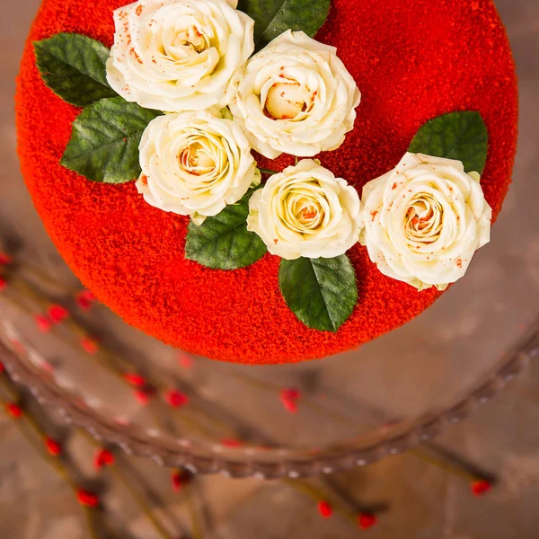 Red velvet cake decorated with white small roses with green leaves. Festive luxury cake for a birthday or wedding