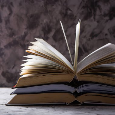Gri bir arka plan üzerinde saygısız sayfaları ile açık kitap yığını. Öğrenme okuma ve kendini geliştirme kavramı