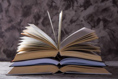 Gri bir arka plan üzerinde saygısız sayfaları ile açık kitap yığını. Öğrenme okuma ve kendini geliştirme kavramı