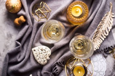 İki bardak şampanya altın ve beyaz Noel süsleri arasında gri bir ekose üzerinde. Üstten görünüm, düz yatıyordu