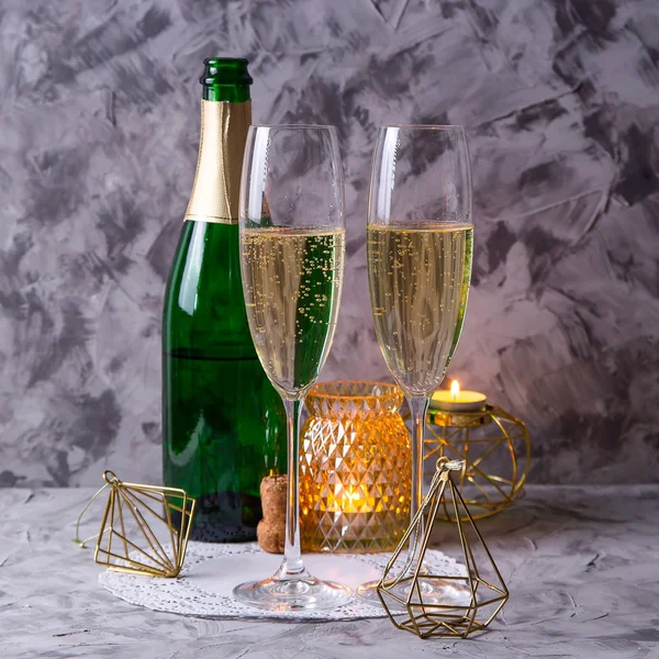 Два Бокала Шампанского Рядом Бутылкой Золотыми Рождественскими Украшениями Свечами Сером — стоковое фото