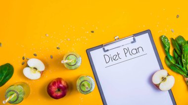 Diyet planı tablet arasında şişe yeşil smoothies, ıspanak ve elma parlak sarı bir arka plan üzerinde beyaz bir kağıda yazılır. Zayıflama ve detoks kavramı