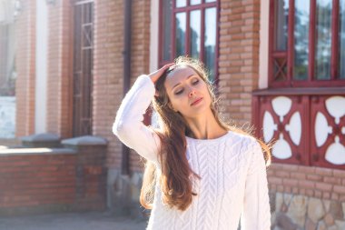 Gülümseyen güneş ışığı açık sarı saçlı beyaz örgü kazak bin yıllık kız. Mutlu hissediyorum