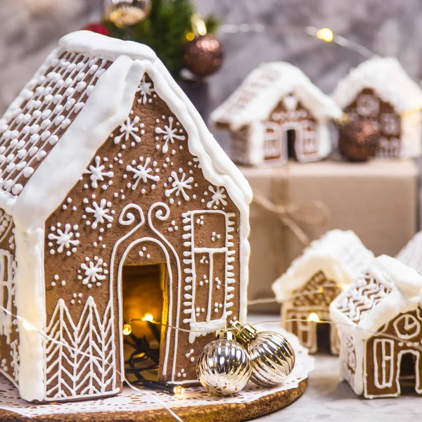 大大小小的姜屋 一个灰色背景上的生姜屋村 有灯光 圣诞装饰和小圣诞树 — 图库照片