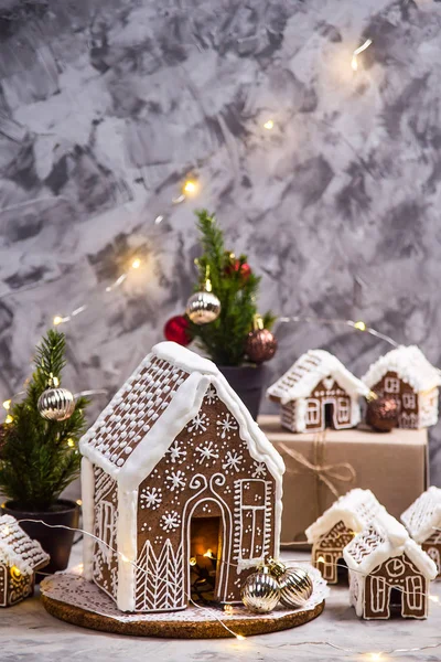 Big and small ginger houses - a village of ginger houses on a gray background with lights, Christmas decorations and small Christmas trees. Stilllife