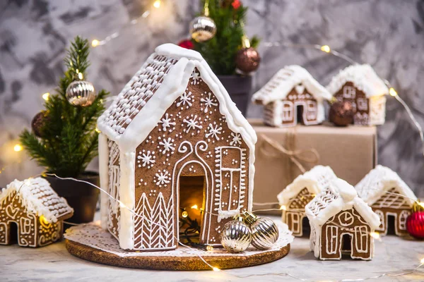 Big and small ginger houses - a village of ginger houses on a gray background with lights, Christmas decorations and small Christmas trees. Stilllife