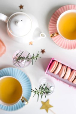 Yeşil çay, yıldız ve dal üzerinde beyaz bir arka plan ile küçük vazo hediye kutusu vintage bardak arasında pembe macaroons ile. Şık tatlı