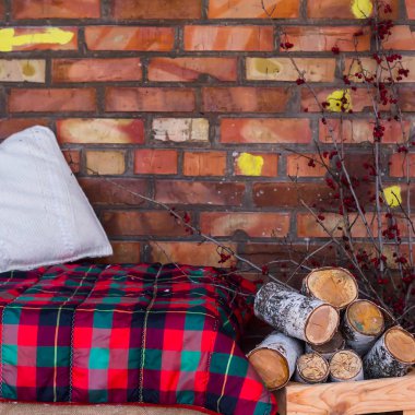 Huş ağacı ahşap koltuk terasta açık kış karla kaplı bir ev tuğla duvar tarafından kırmızı battaniye ile yakınındaki bir yığın. Rahat iç kış yazlık