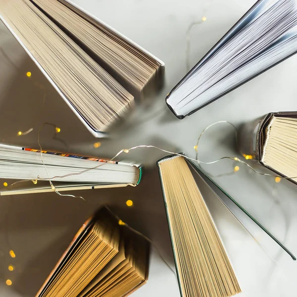 Kitap bir Garland sarı ışıklar bir masada hazır. Okuma kavramı. Üstten görünüm, düz yatıyordu
