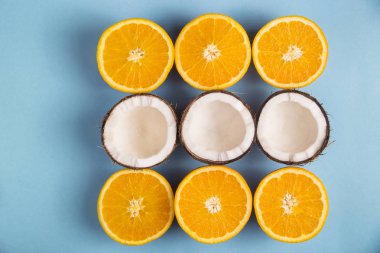 Sulu olgun portakal ve parlak mavi arka plan karede ile kaplı beyaz Hindistan cevizi yarısı. Üstten Görünüm, düz yatıyordu