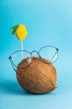 Kabuklu meyve parlak mavi arka plan ile dekore edilmiş iyi adam ile şık bardaklarda bütün kahverengi Hindistan cevizi