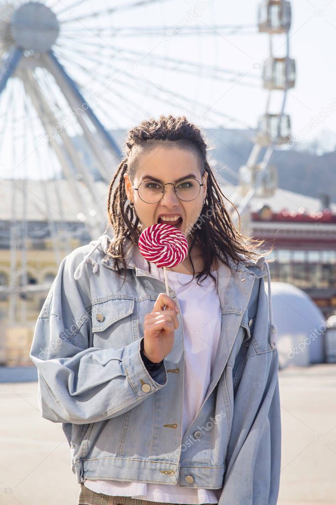 Beautiful caucasian girl with a lollipop in an amusement park