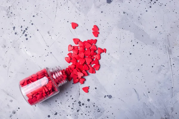 Pequeños corazones rojos en una mesa gris como símbolo de amor en Valentin — Foto de Stock