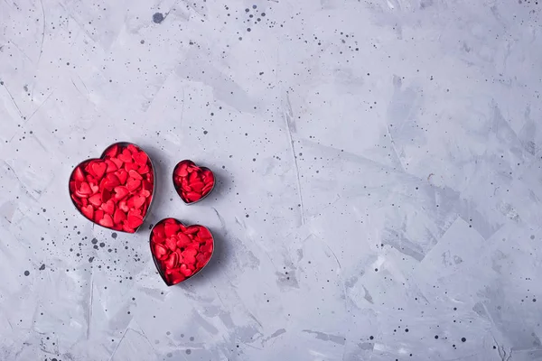 Red small hearts on a gray table as a symbol of love on Valentin — Stock Photo, Image