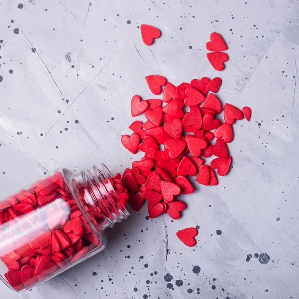 Pequenos corações vermelhos em uma mesa cinza como um símbolo do amor em Valentin — Fotografia de Stock