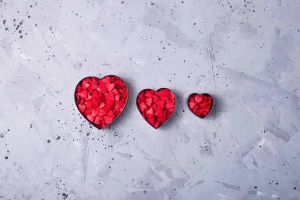 Pequenos corações vermelhos em uma mesa cinza como um símbolo do amor em Valentin — Fotografia de Stock