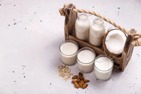 Gri bir masada hindistan cevizi, yulaf ezmesi ve badem vegan süt