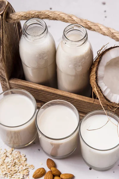 Gri bir masada hindistan cevizi, yulaf ezmesi ve badem vegan süt