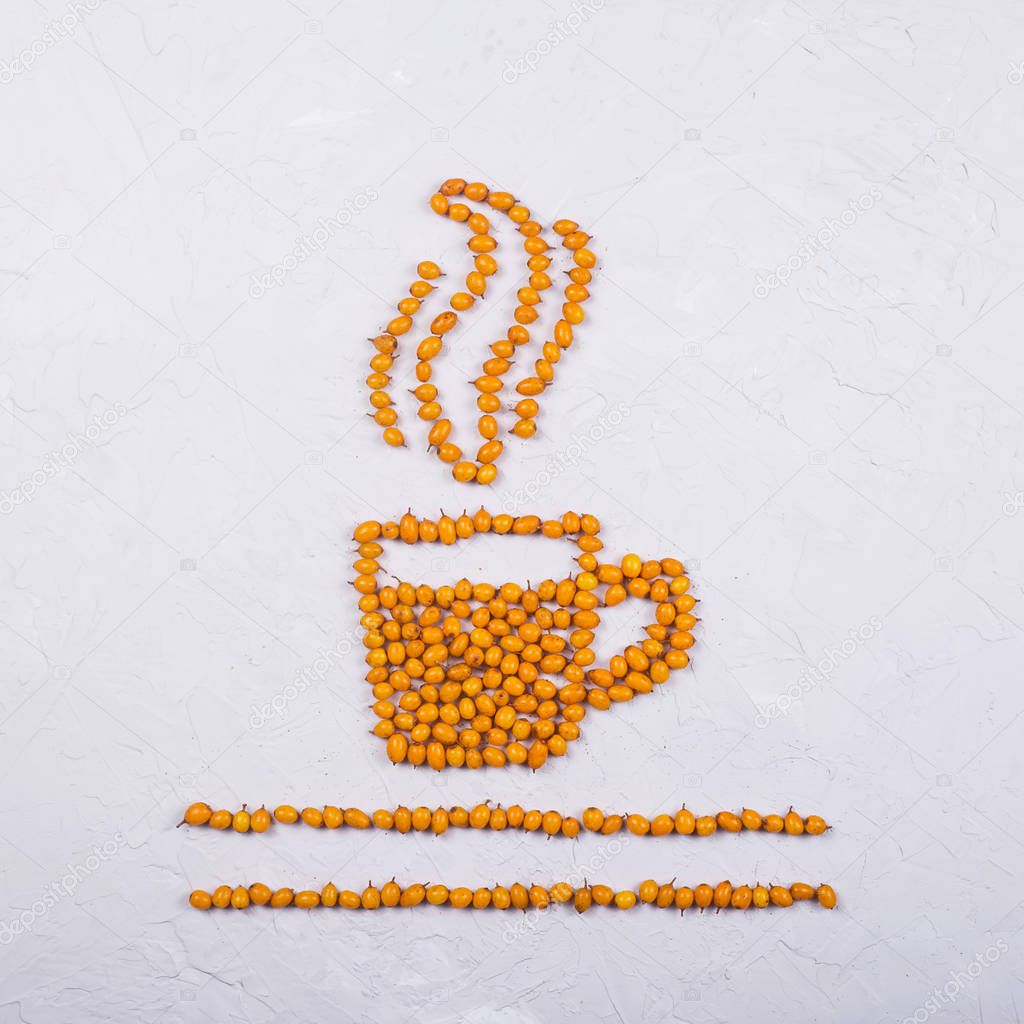 A layout of bright orange sea buckthorn berries in the shape of a cup of tea with steam. Autumn creative concept. Top view, flat lay