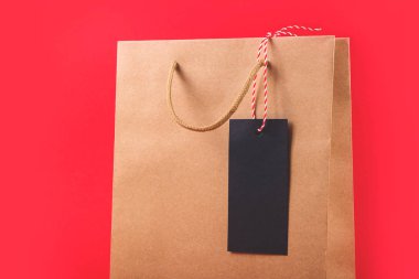 Parlak kırmızı arkaplanda siyah cuma günü satın alma etiketi olan Kraft kağıt çantası.