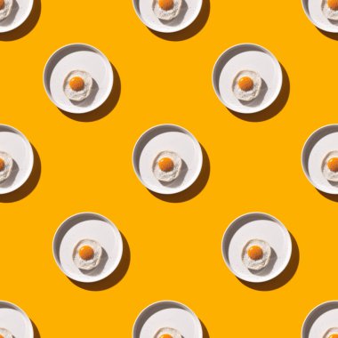 Saf gölgeli sarı bir masada yuvarlak bir tabakta pürüzsüz yumurta deseni. Yemek pişirmede yaratıcılık ve minimalizm kavramı.