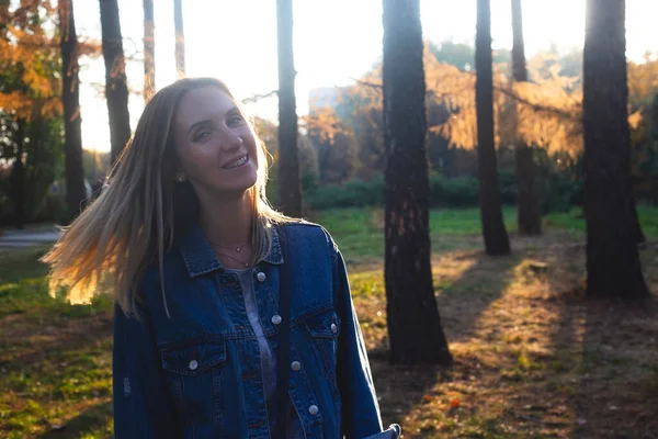 Menina sorrindo enquanto caminhava no parque de outono ao pôr do sol . — Fotografia de Stock