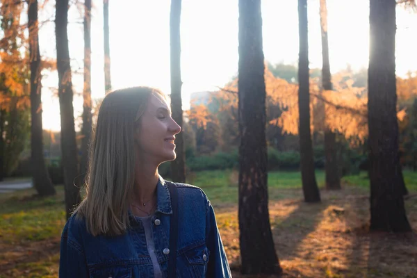 Menina sorrindo enquanto caminhava no parque de outono ao pôr do sol . — Fotografia de Stock