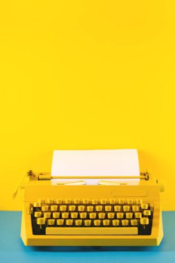Sarı ve mavi arka planda sarı parlak daktilo. Yazma, blog yazma, yeni fikirler ve yaratıcılık sembolü. Boşluğu kopyala