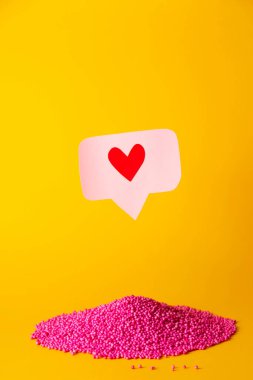 Pembe topların üzerindeki pembe bir iğnenin üstündeki kalp ikonu gibi kırmızı. Sosyal ağlar kavramında birçok emoji kalbi