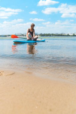 Güzel bir kadın yazın aktif spor yapıyor. Nehirde SUP panosunda.