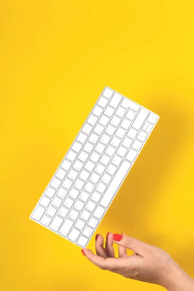 Tangentbord saldon på kvinnor hand på gul bakgrund — Stockfoto