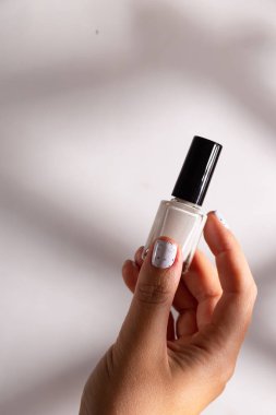 Şişede beyaz oje ve manikürde kadın manikürü.